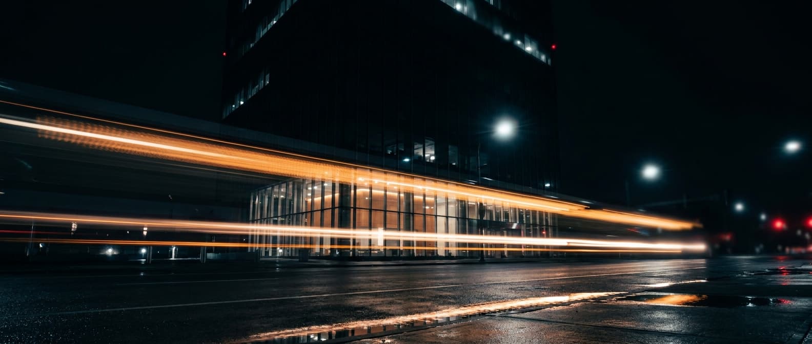 An exchange tower at night, light streaking across wet asphalt